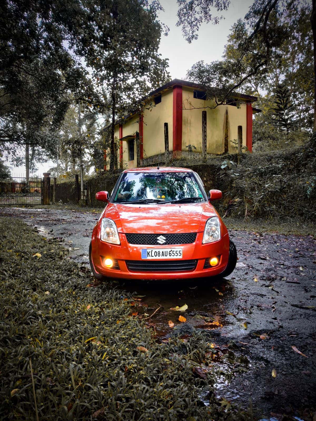 A red Suzuki Swift parked in South India